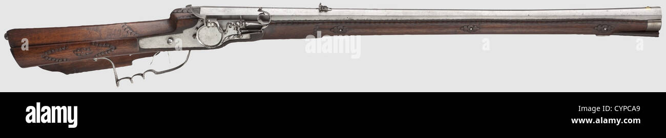 A rare matchlock target rifle,Cornelius Klett,Salzburg,dated 1671. Heavy octagonal barrel,swamped at the muzzle,with a six groove rifled bore in 17 mm calibre. Dovetailed brass front sight and iron,folding leaf rear sight. The chamber bears the brass filled mark 'CK'(Stöckel No. 7699)of Cornelius Klett within the date 1671. Cut matchlock,worked in the style of a wheellock,with a swinging pan cover and a double set trigger. Carved walnut full stock with iron furniture. The patch box contains the original iron powder measure,numbered '12'. Wooden ramro,Additional-Rights-Clearences-Not Available Stock Photo
