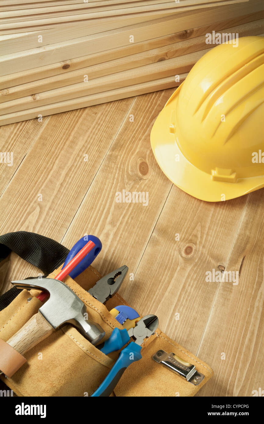 Construction background. Yellow helmet and tool belt on wooden floor. Stock Photo