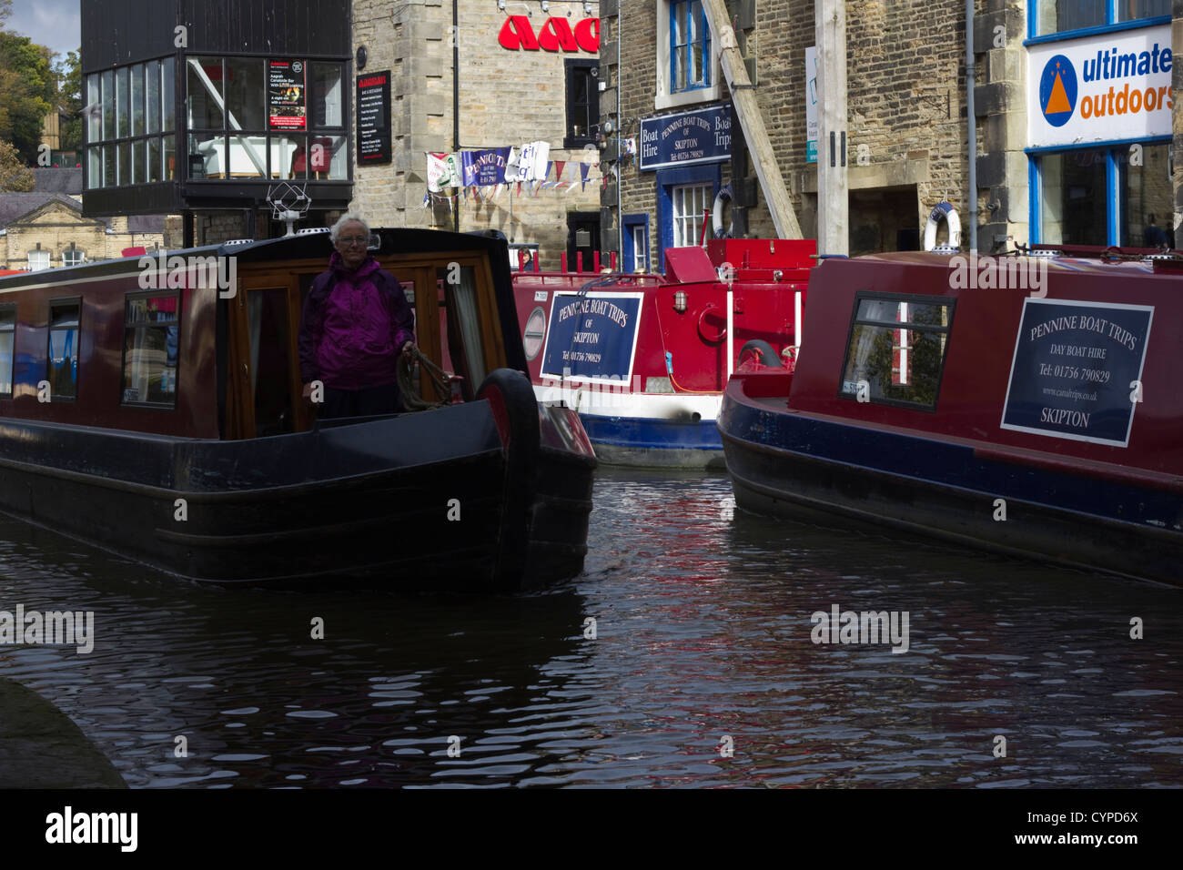 Narrow boat passing moored barges on the Leeds and Liverpool Canal Stock Photo