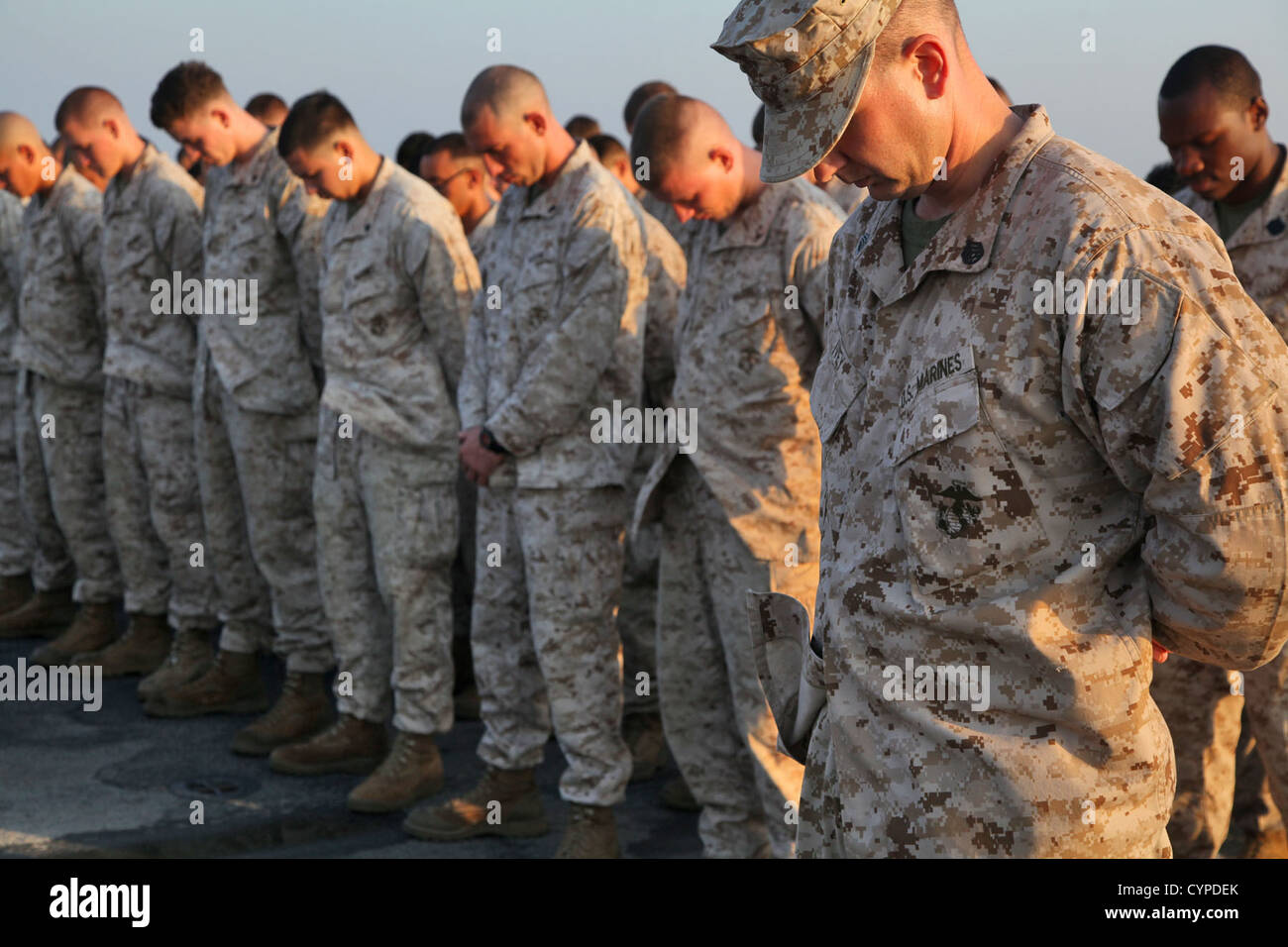 Marines from the 15th Marine Expeditionary Unit bow their heads in prayer during an early Marine Corps Birthday celebration on the flight deck of the USS Rushmore, Nov. 7. The 15th MEU is deployed as part of the Peleliu Amphibious Ready Group as a theater Stock Photo