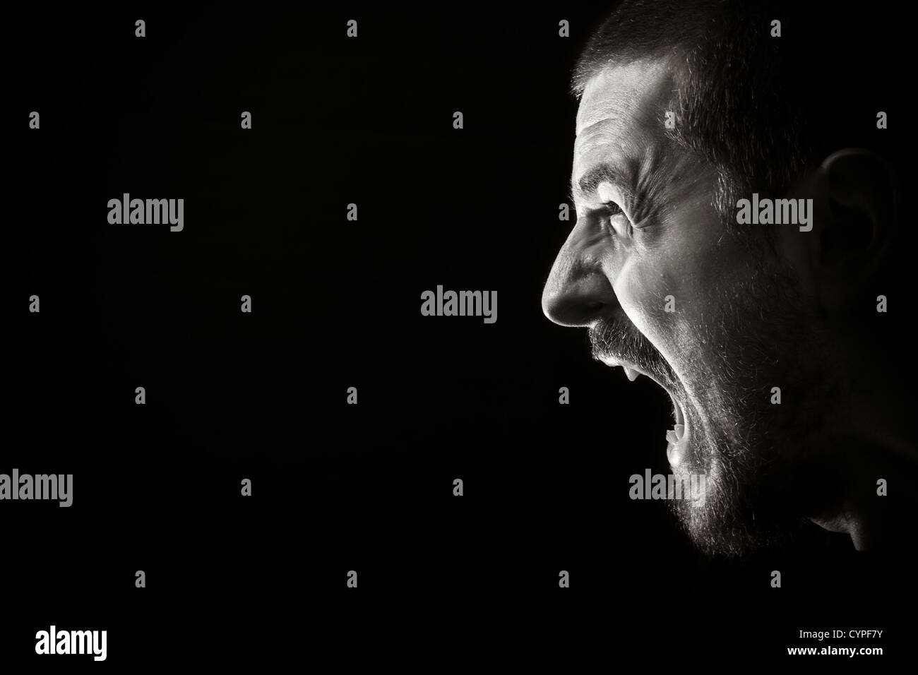 Portrait of screaming angry man on black background Stock Photo