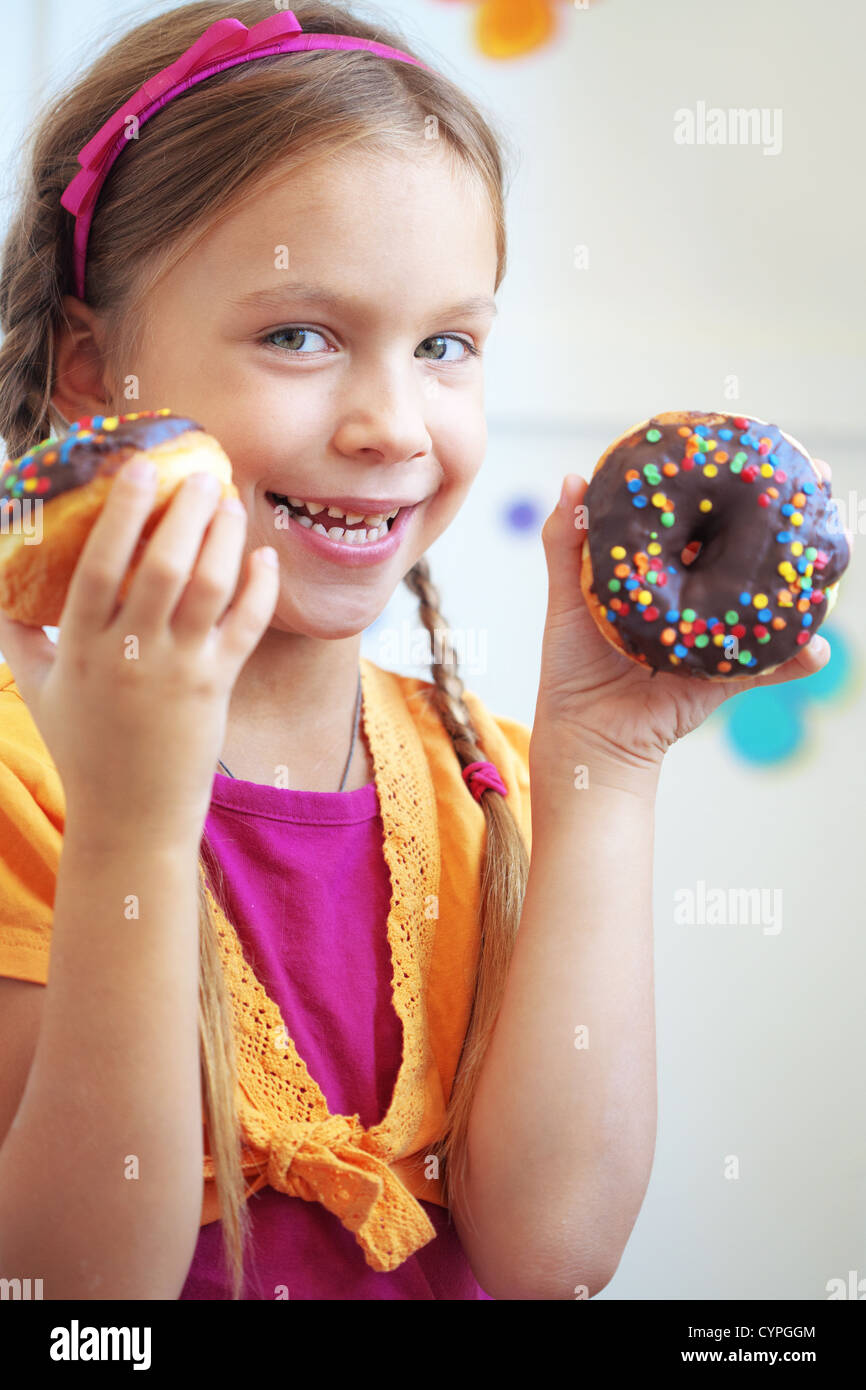 Cute kid girl eating sweet donuts Stock Photo