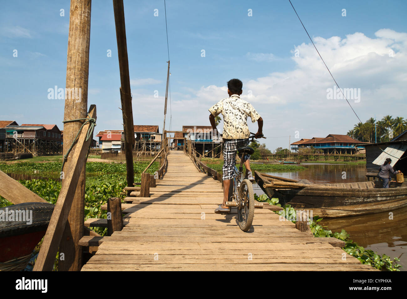 Boy on a Bike in the Stilt Village Kampong Khleang in the North of Cambodia during the dry Season Stock Photo