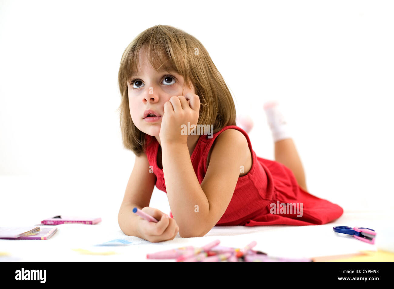 Focused little girl is lying and holding a crayon Stock Photo