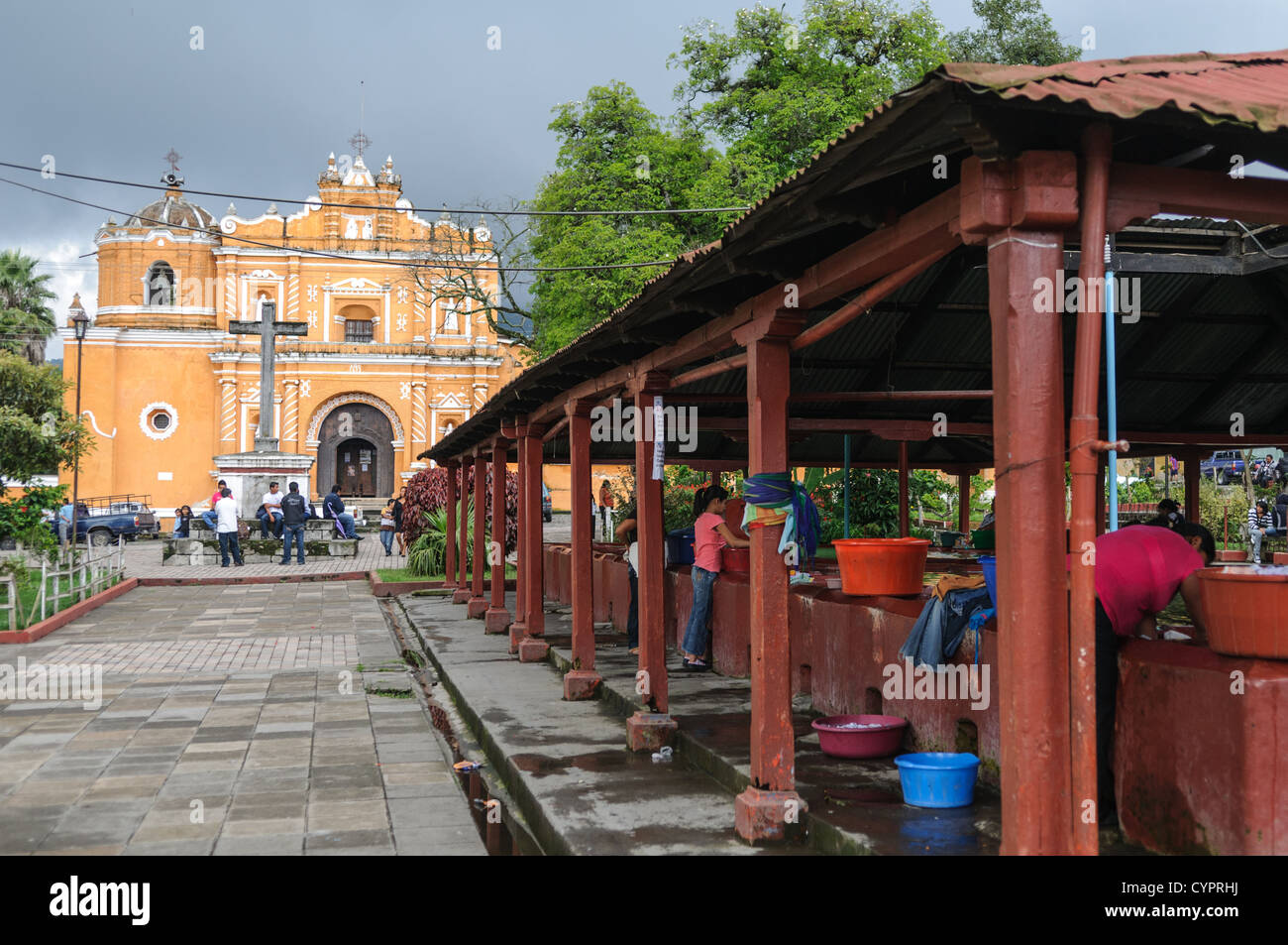 The burnt sienna colored Iglesia en San Pedro las Huertas, about 15 minutes away from Antigua, Guatemala. At right are communial washing areas. Stock Photo