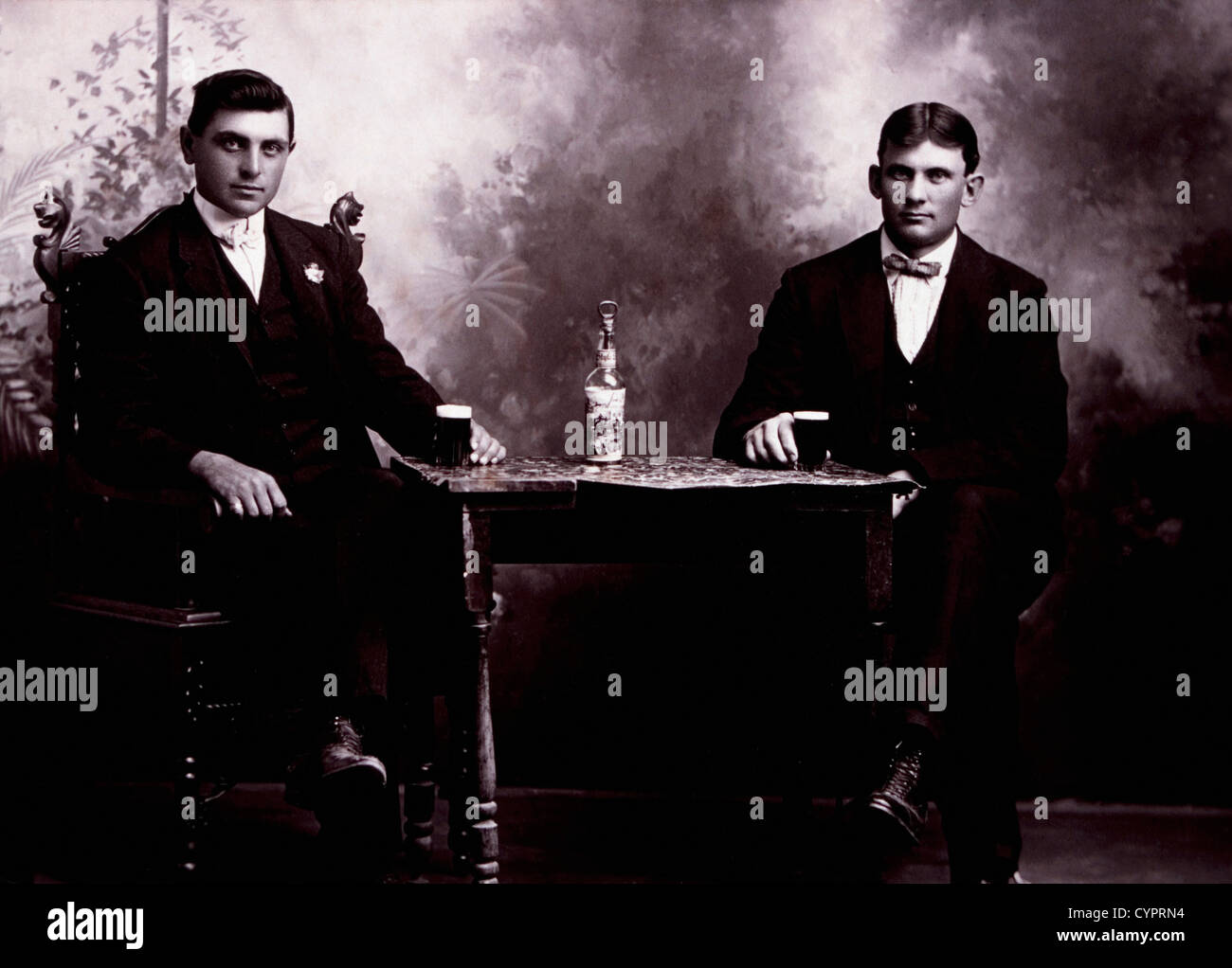 Two Men in Formal Attire Sitting at Table Drinking Beer, Circa 1900 Stock Photo
