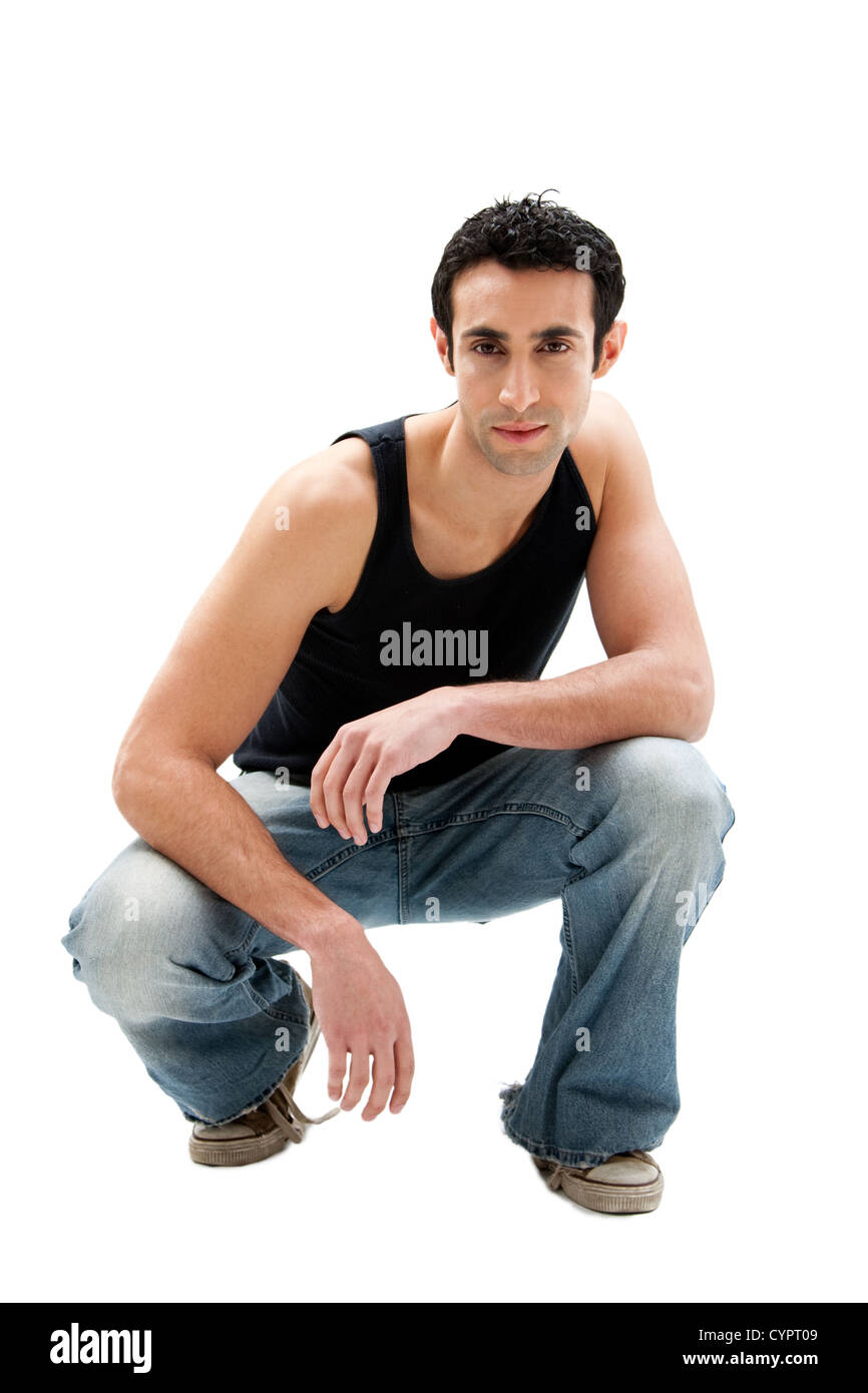 Handsome serious Caucasian guy wearing black tank top and jeans squatting,  isolated Stock Photo - Alamy