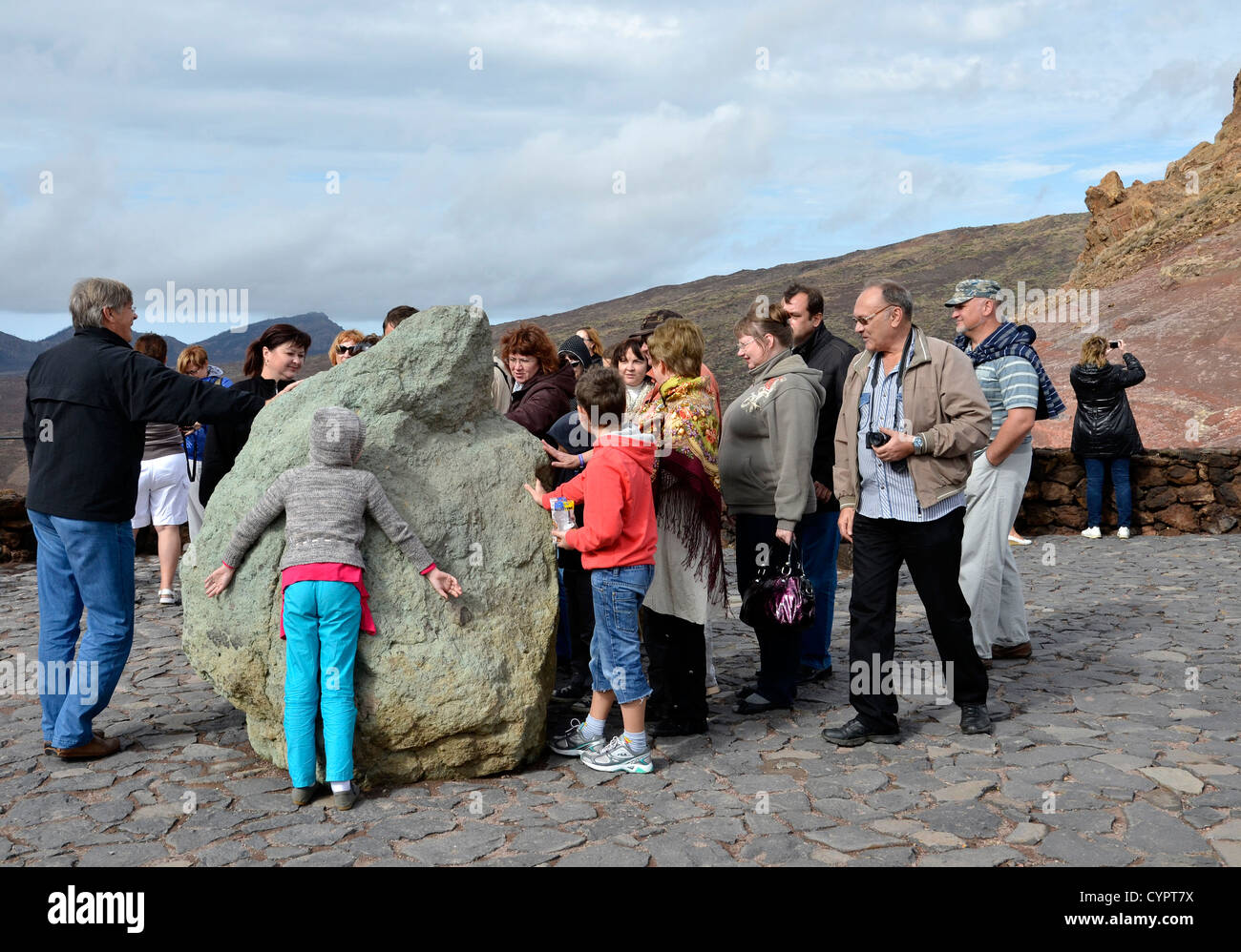 Tourists hugging a rock at Roques De Garcia near Mount Teide in the National park Canadas del Teide, Tenerife. Stock Photo
