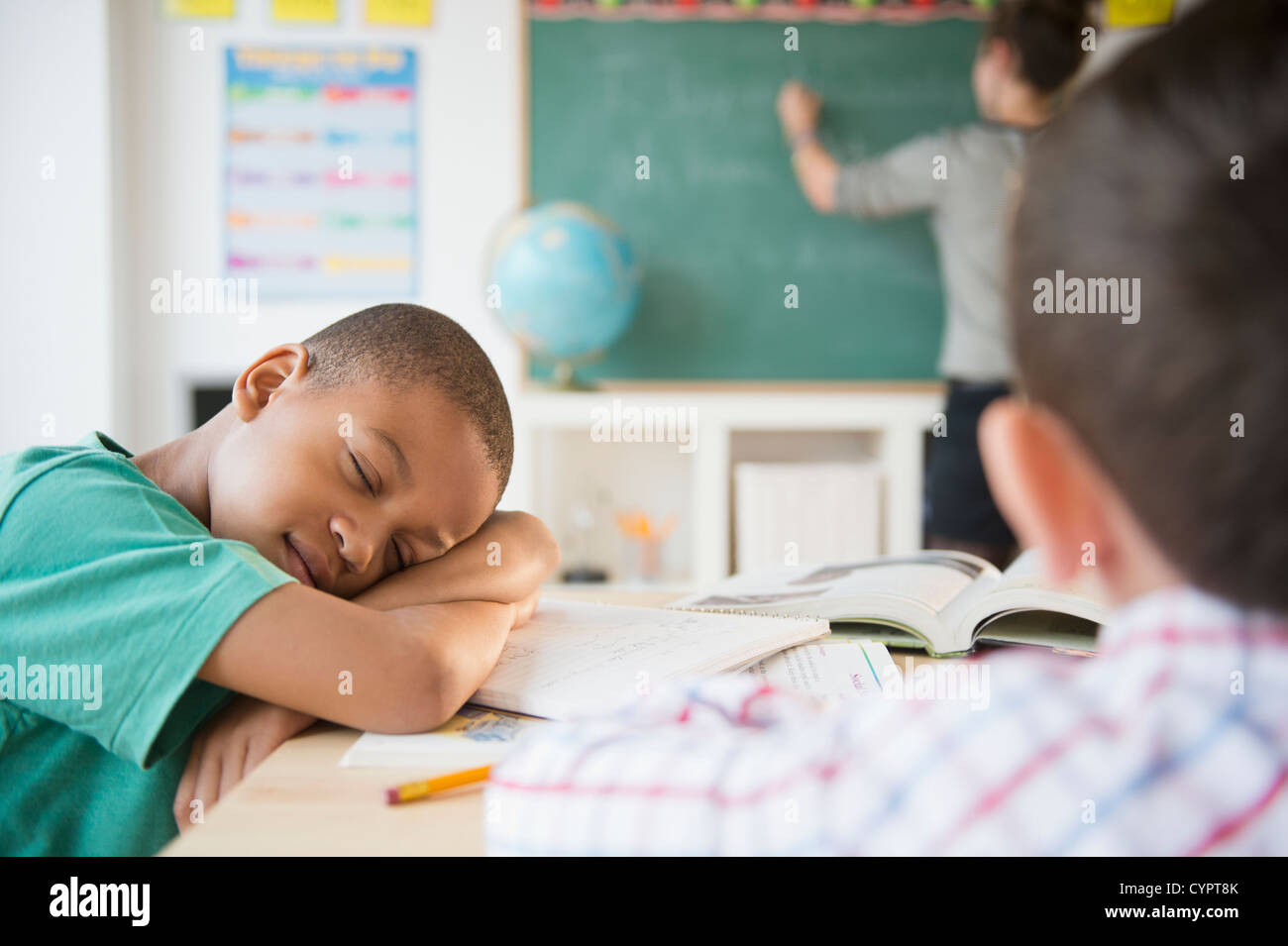 African American boy sleeping in classroom Stock Photo