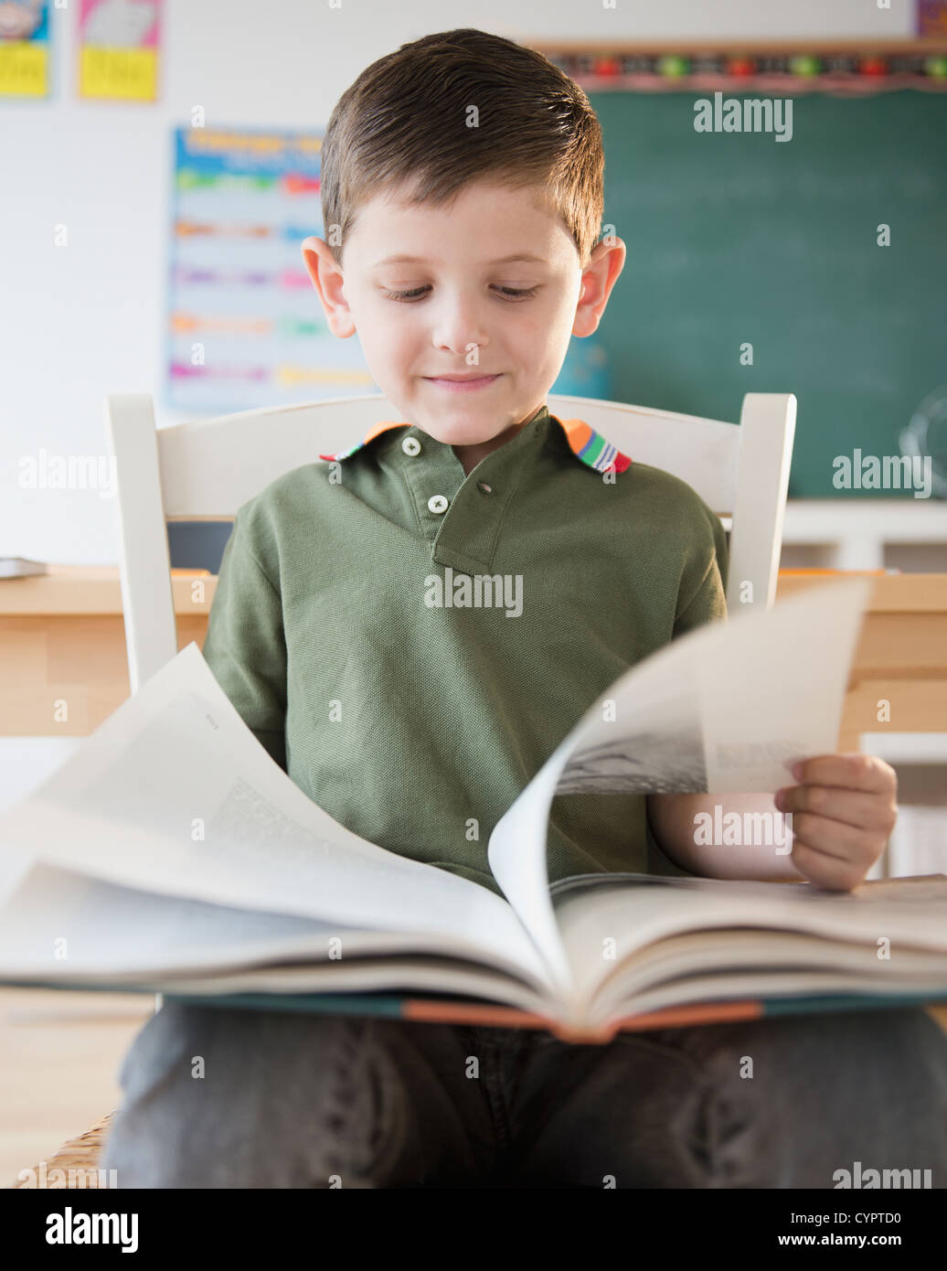 Caucasian boy reading book in classroom Stock Photo