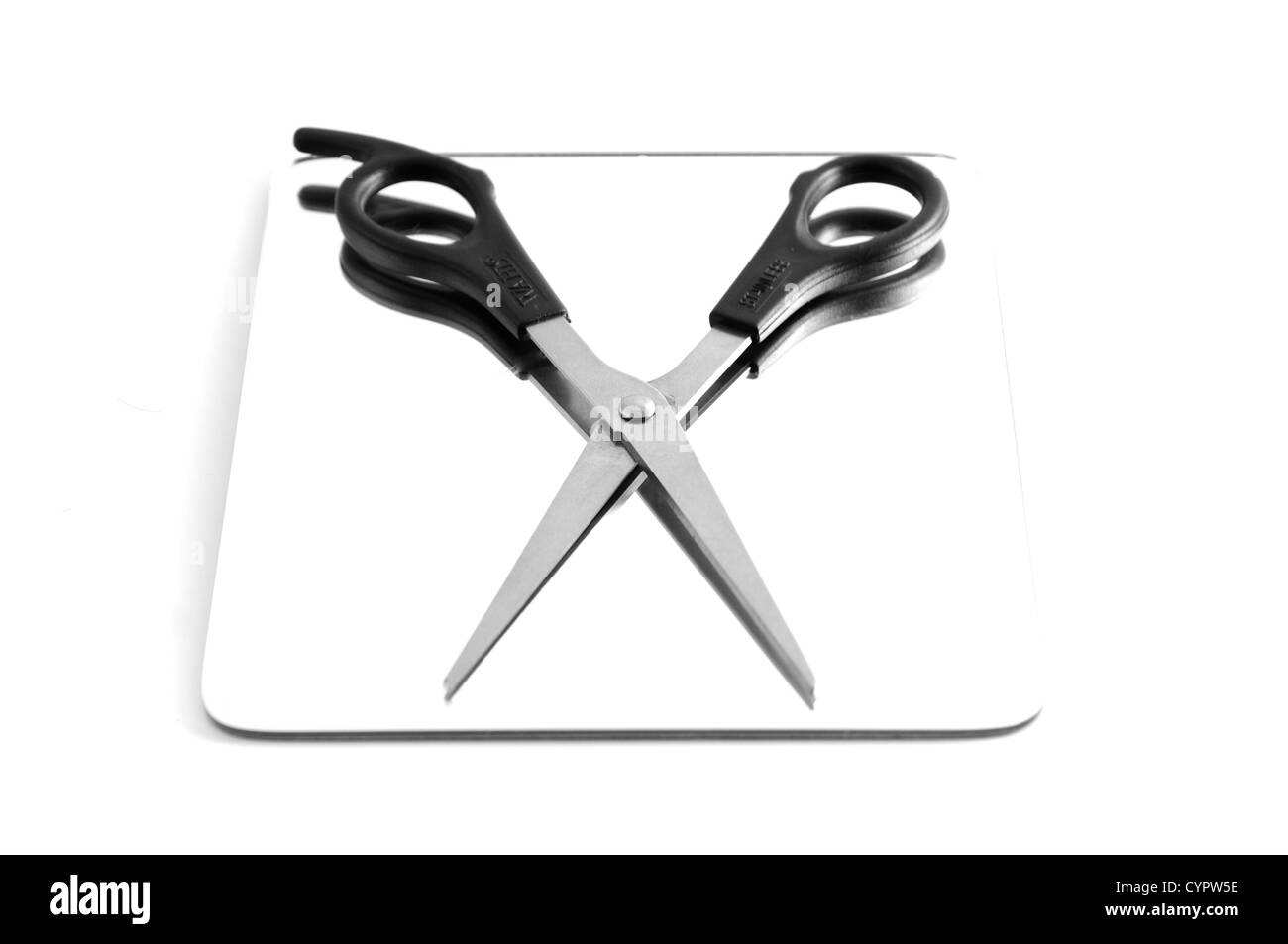 Isolated Hairdressers scissors lying on top of a mirror Stock Photo