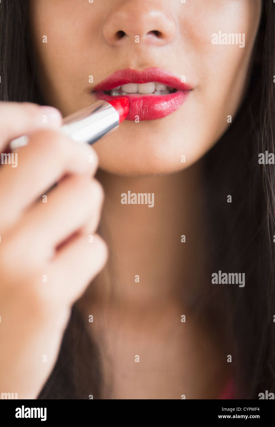 Hispanic teenager putting on lipstick Stock Photo