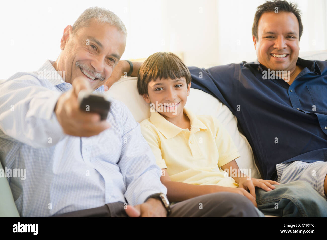 Hispanic grandfather, father and son watching television Stock Photo