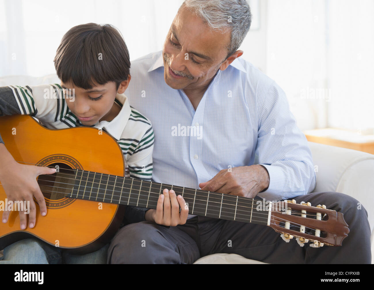 Hispanic grandfather watching grandson playing guitar Stock Photo