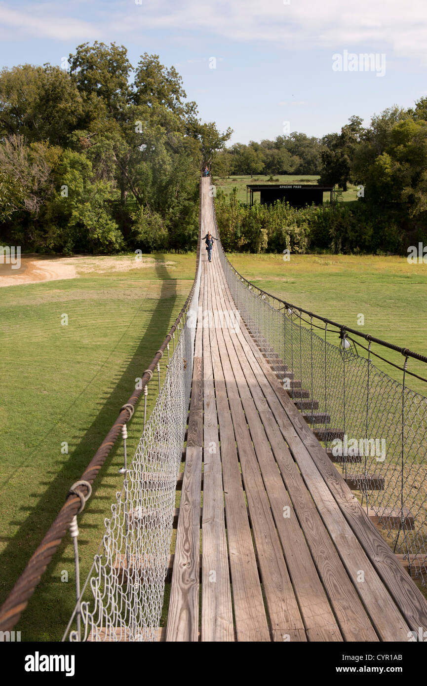 Junior high school students walk across a wood-plank swinging bridge over the San Gabriel River in central Texas Stock Photo