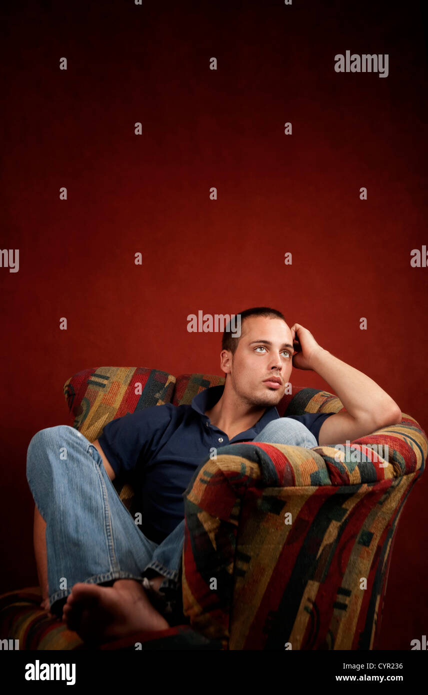 Handsome young man reclining in a colorful chair Stock Photo - Alamy