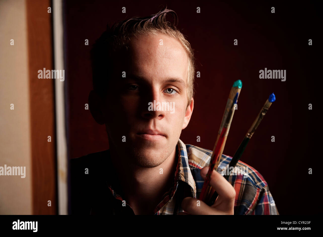 Handsome young artist holding brushes Stock Photo Alamy