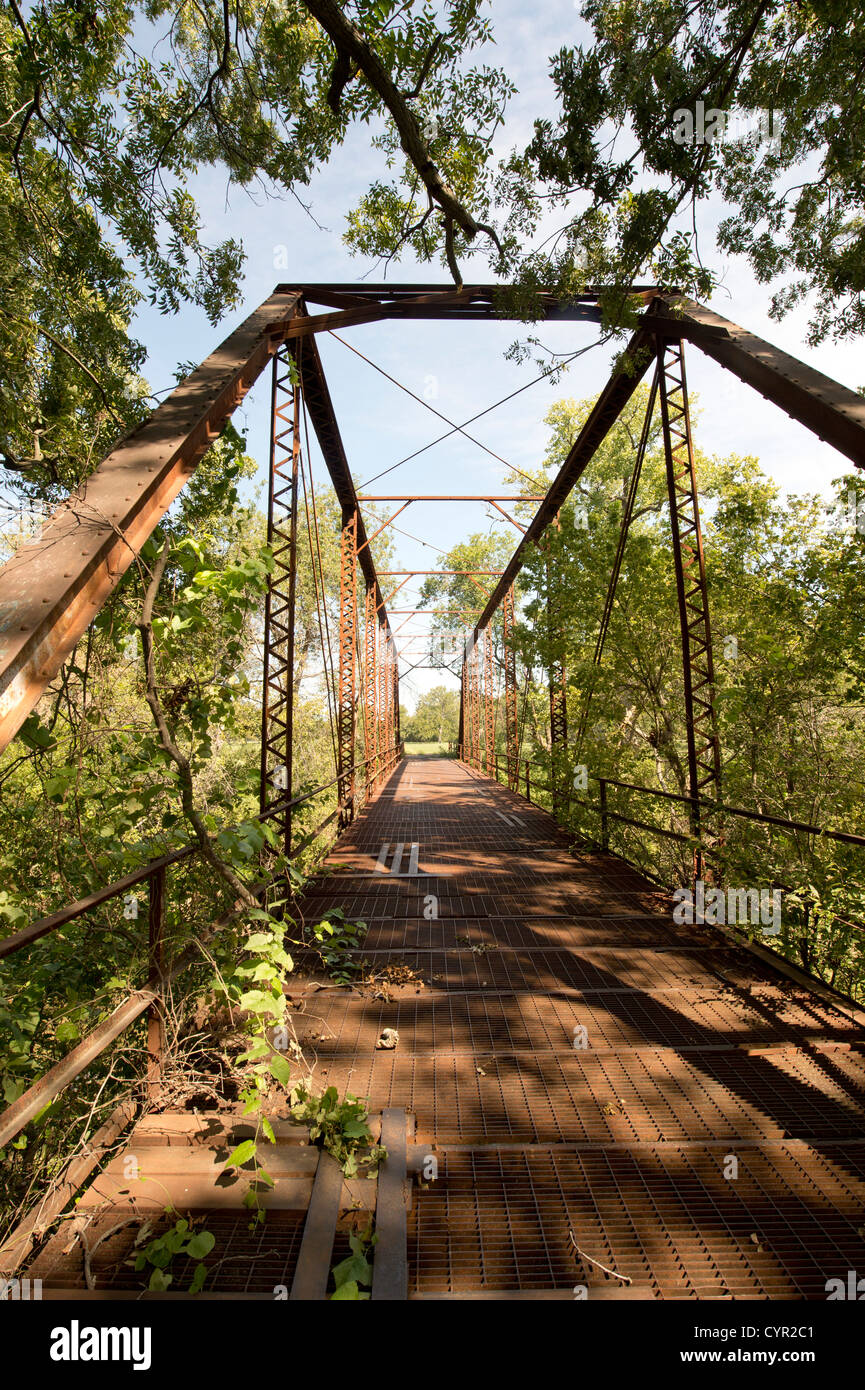 An abandoned one-lane county road and steel truss bridge over the San Gabriel River in central Texas Stock Photo