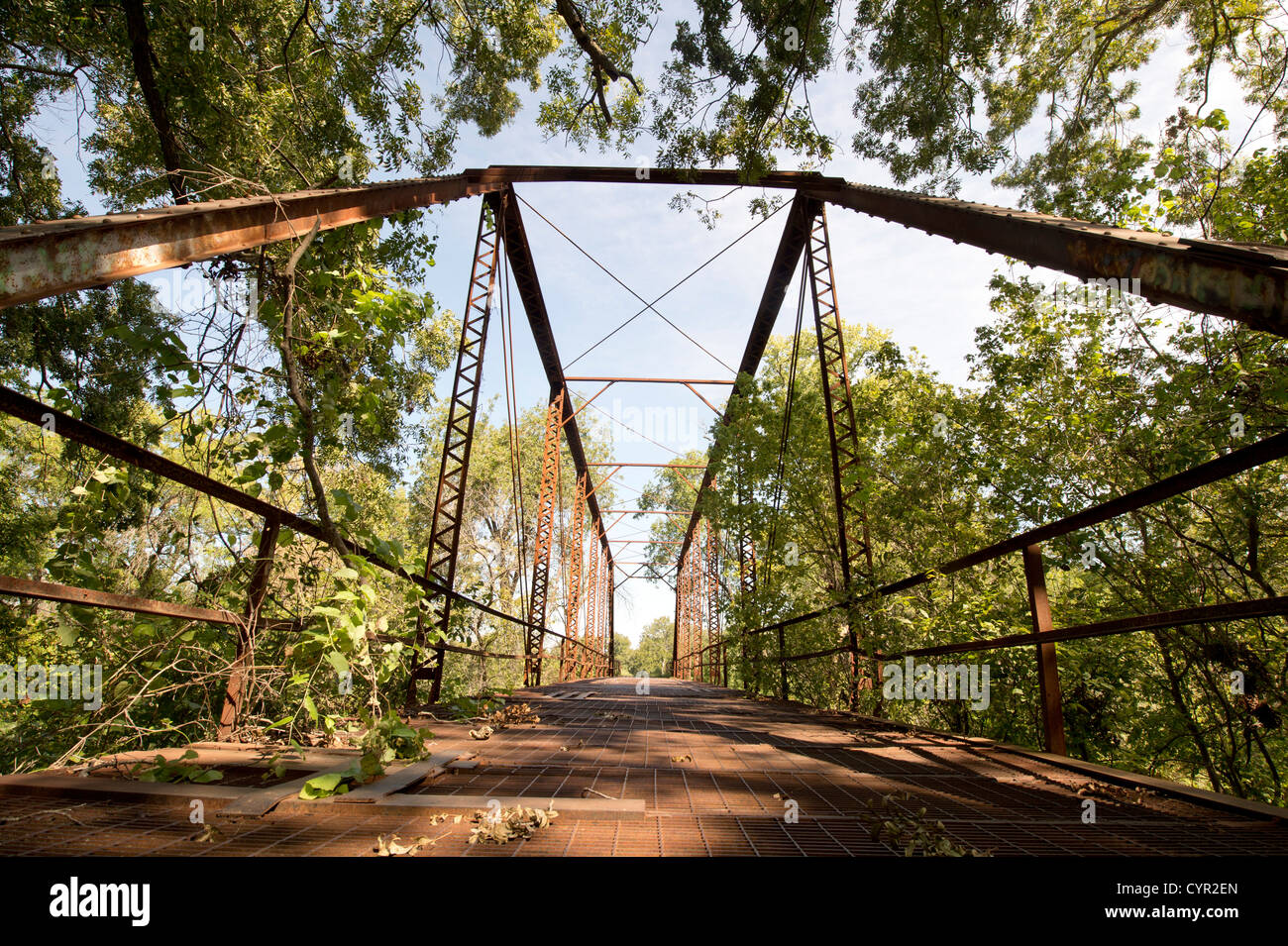 An abandoned one-lane county road and steel truss bridge over the San Gabriel River in central Texas Stock Photo