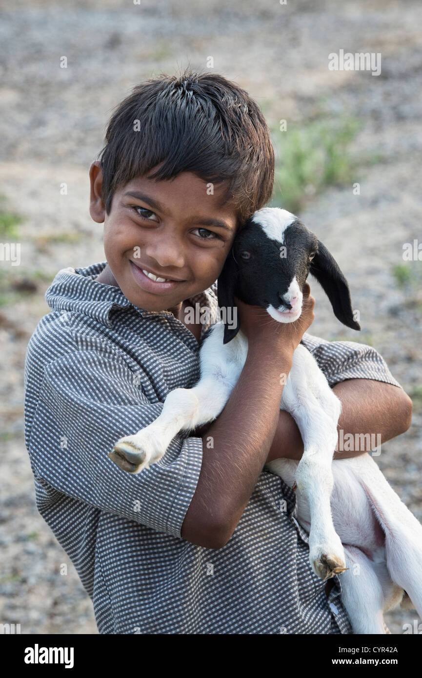 Indian goat herder boy holding a baby goat (kid) in the indian