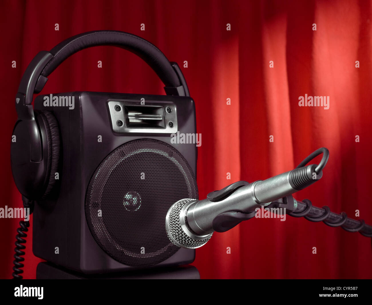 Professional microphone, headphone and speaker with a red curtain on the background. Stock Photo
