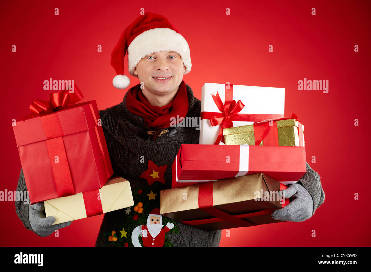 Portrait of happy man in Santa cap holding giftboxes and smiling at ...