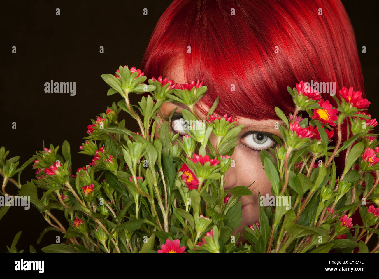 Pretty punky girl with brightly dyed red hair and flowers Stock Photo