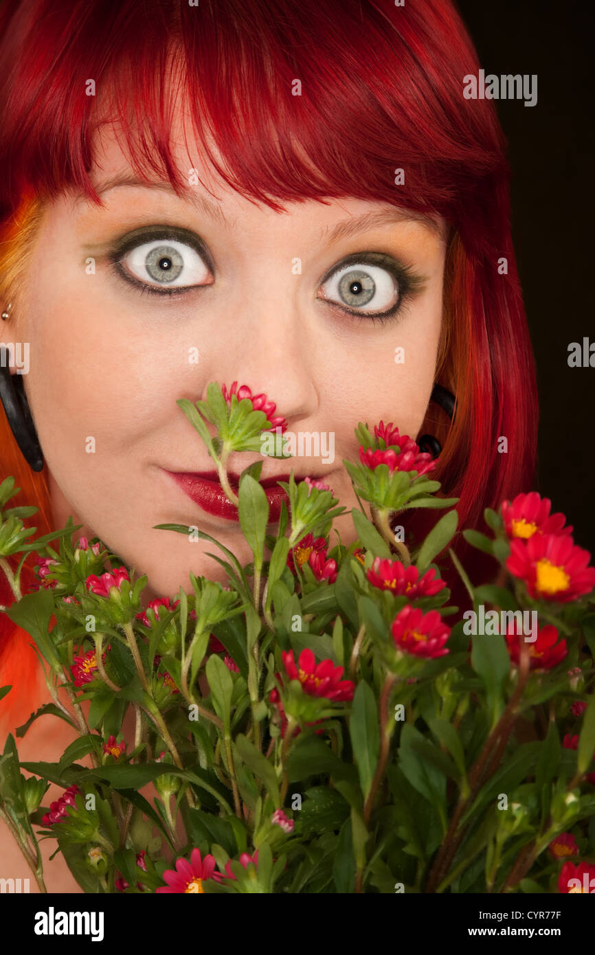 Pretty punky girl with brightly dyed red hair and flowers Stock Photo