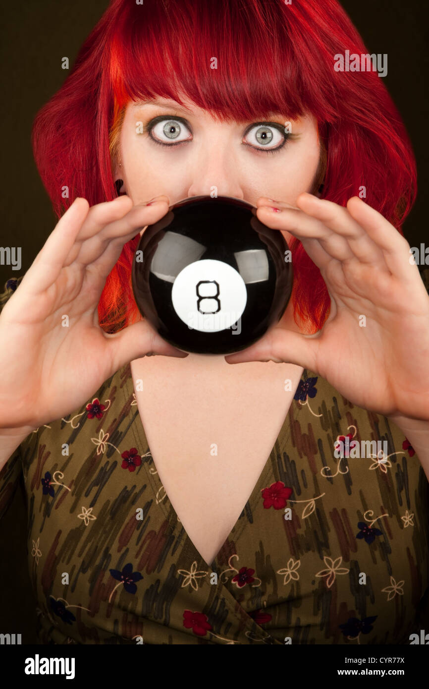 Pretty punky girl with brightly dyed red hair with prediction ball Stock Photo