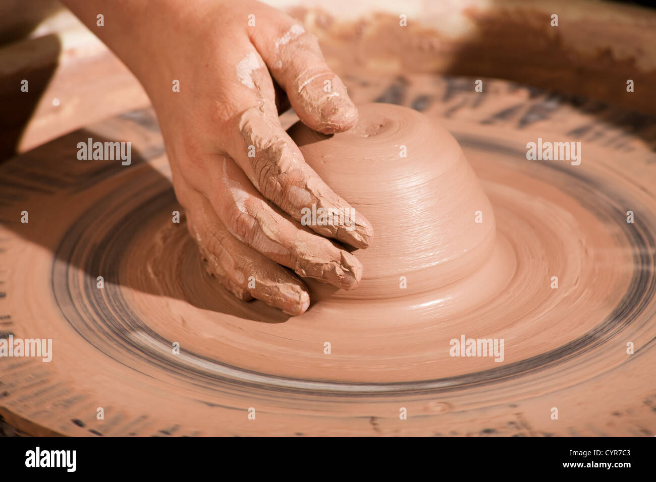 Potter shaping wedge of clay on spinning wheel Stock Photo