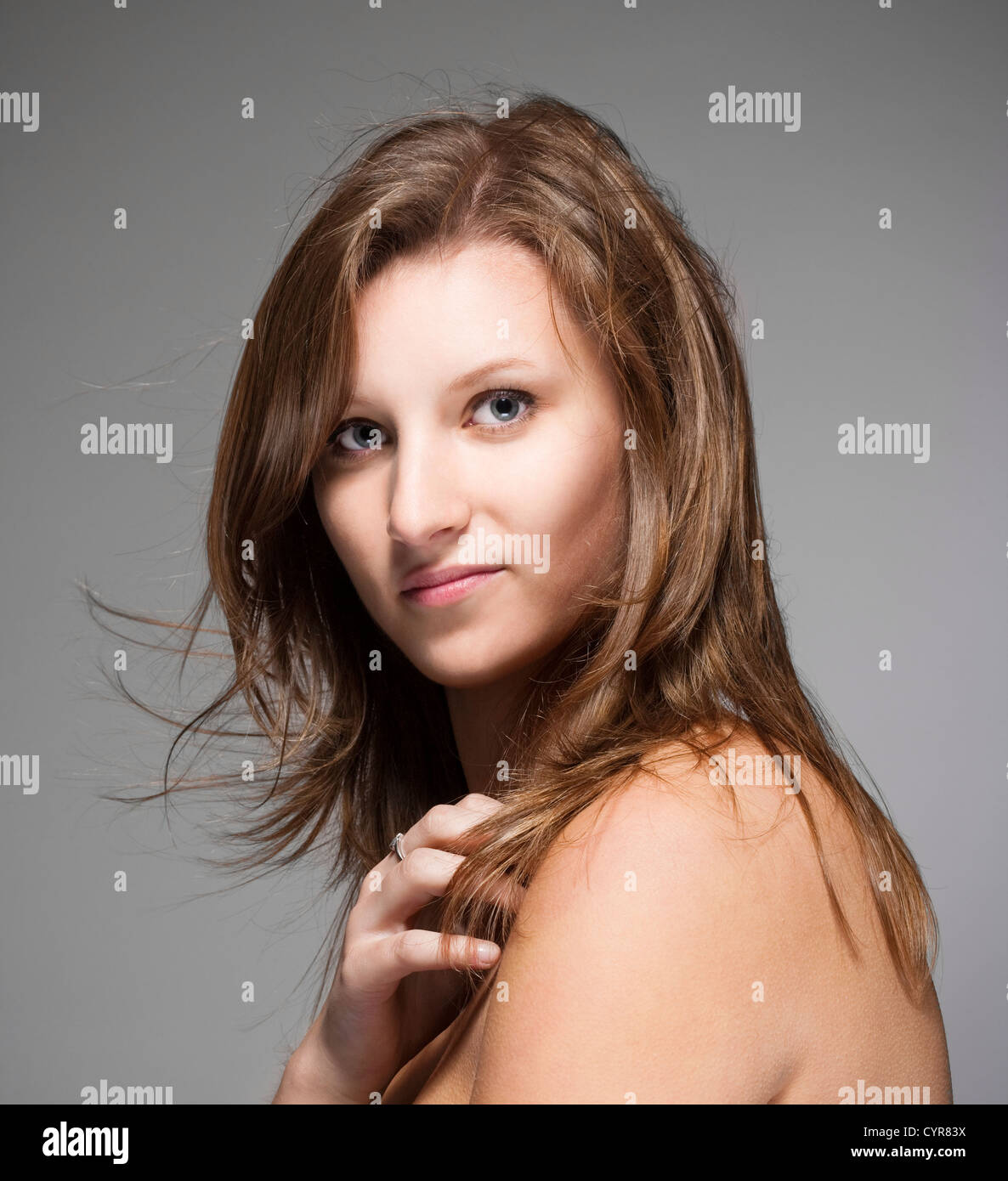 portrait of a young beautiful woman with brown hair against gray ...