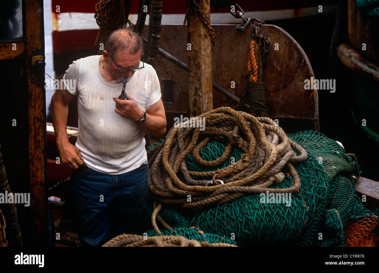 A fishermen looks at rope, nets and tackle in his home port of Tarbert on the western Scottish Mull of Kintyre. Stock Photo