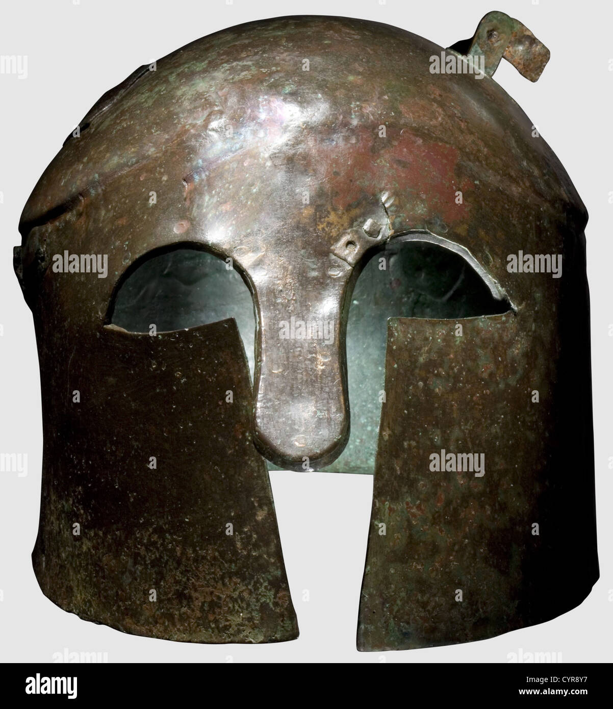 A Corinthian type helmet,6th/5th century B.C. Bronze. Compact skull with slightly offset and flattened calotte,indistinct brow gable and long,closely set cheek pieces,remains of a crest holder riveted to the calotte. Large eye cutouts,massive nose-guard(ancient repair)attached from the inside to the eyebrows by eleven rivets. Narrow flange at the nape. On either side a pierced hole for the attachment of a chinstrap,on the right side two affixed oblong sheets(ancient repair). Height 17.5 cm,weight 788 g. Red-brown patina,partially green corrosion,sli,Additional-Rights-Clearences-Not Available Stock Photo