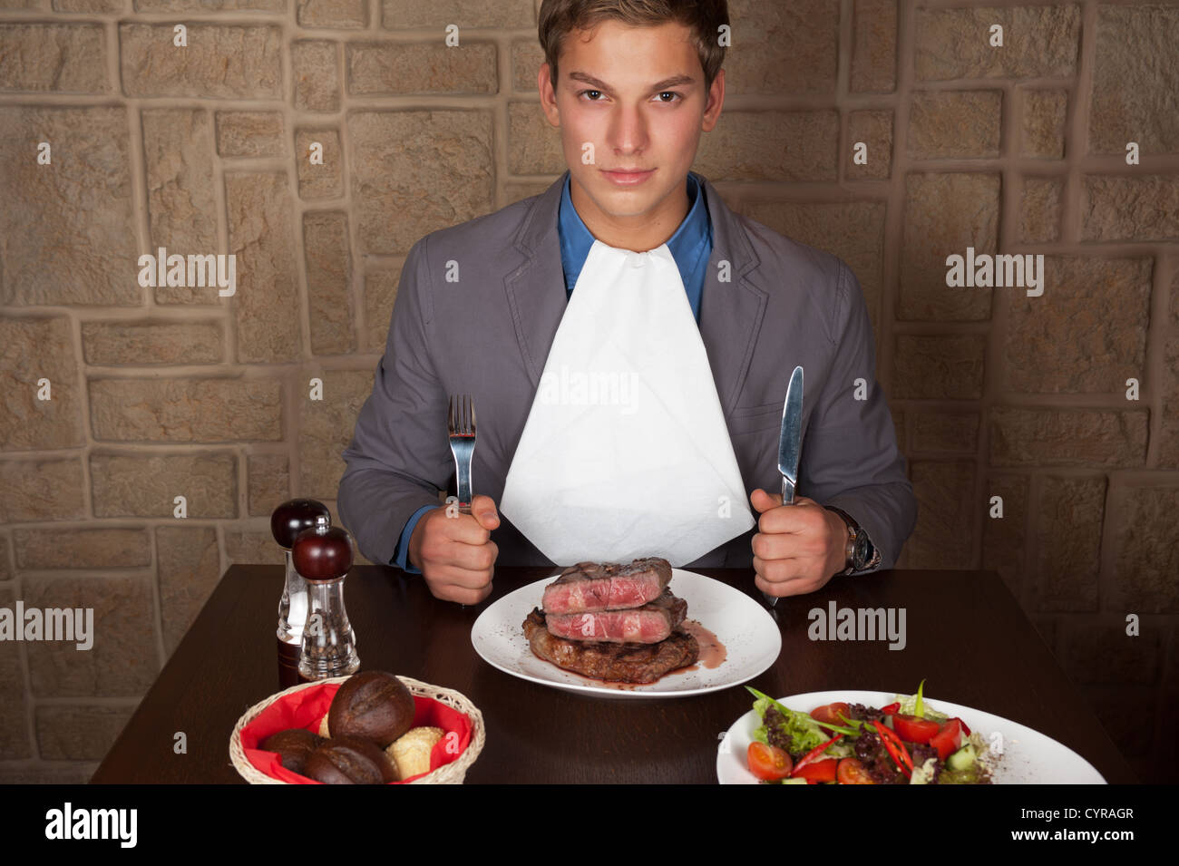 man holding a knife and a fork ready to eat a beef steak Stock