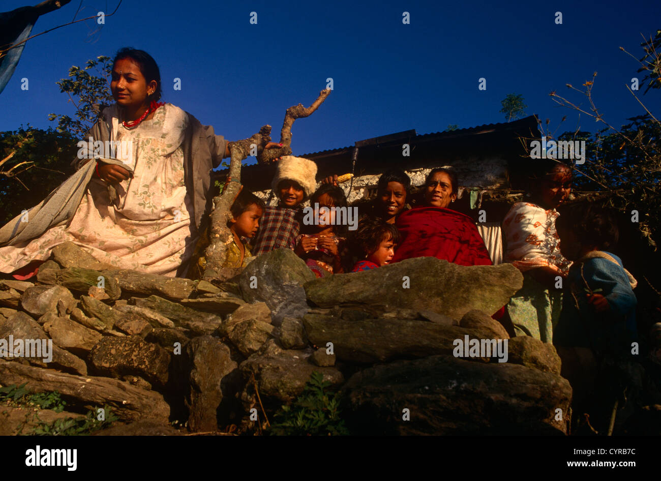 A Nepali family consisting of parents and young children outside their home in the central region of Himalayan mountain kingdom. Stock Photo