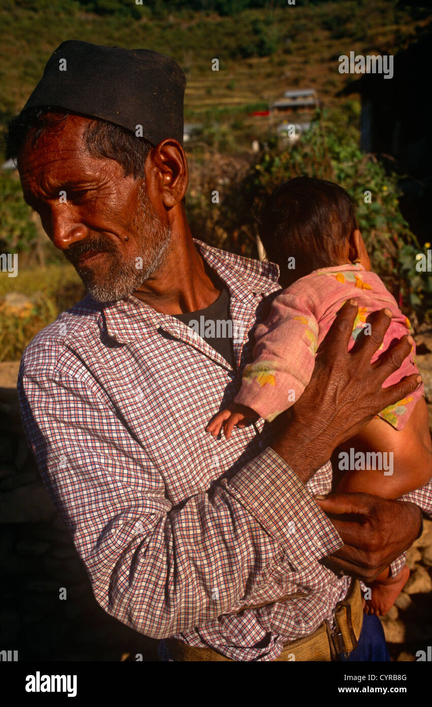 An old man holds a young child near their home in the central region of the Himalayan mountain kingdom of Nepal. Stock Photo