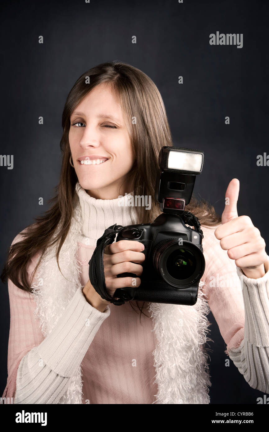 Pretty photographer with a professional camera and flash gives Thumbs