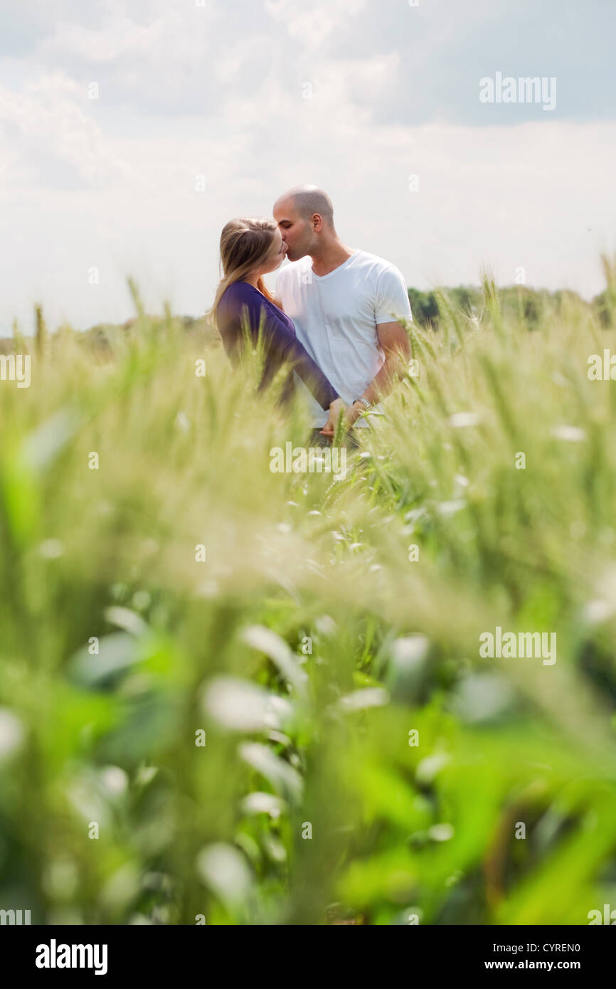 Long shot of the couple giving mouth kiss in the meadows Stock Photo