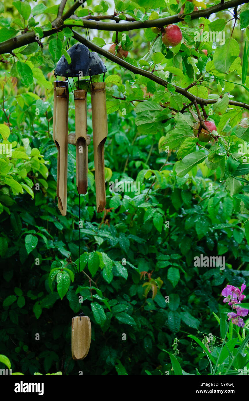 A bamboo wind chimes hanging in an apple tree in a garden Stock Photo