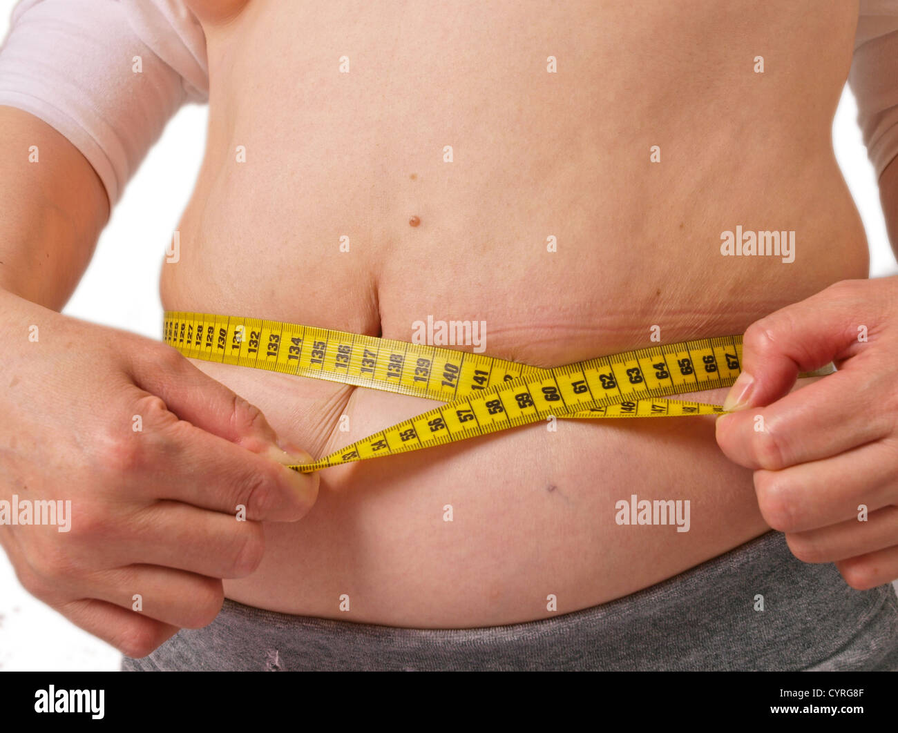 Overweight female. Waist circumference measured. White background Stock Photo