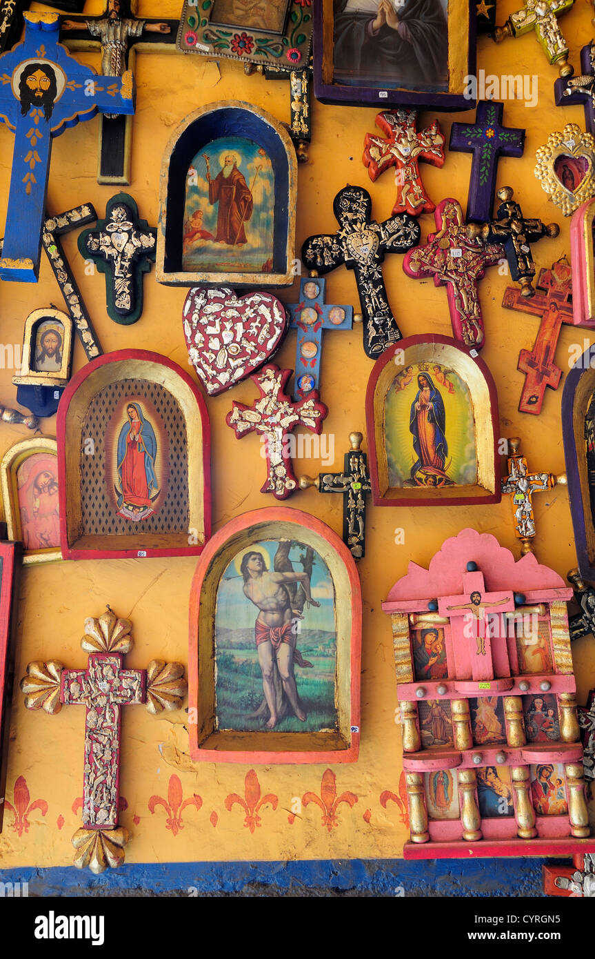 Religious kitsch art displayed on yellow painted wall American  Hispanic Latin America Latino Mexican Religion Shops Shoppers Stock Photo
