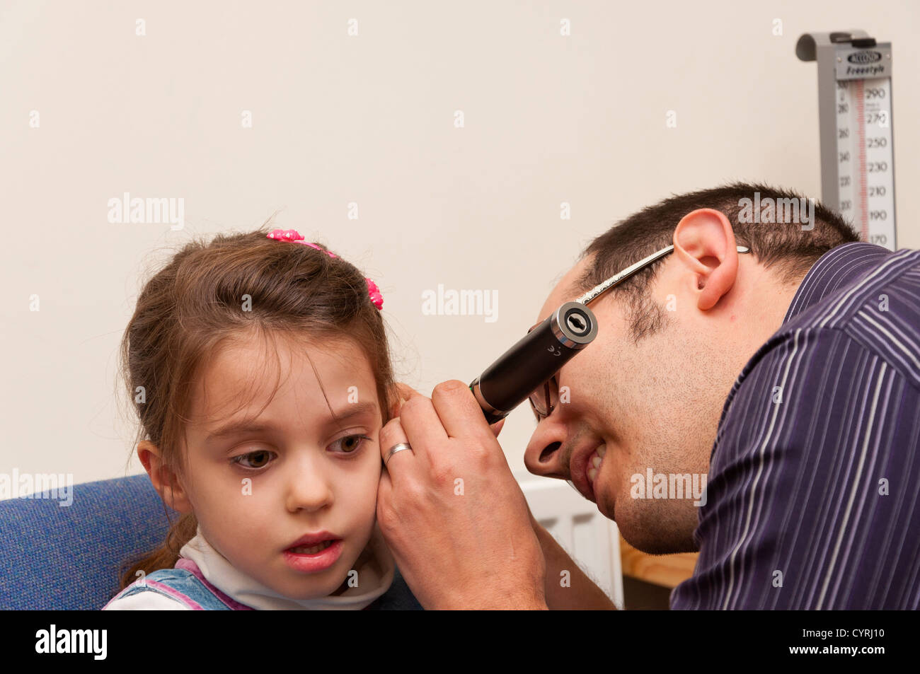 GP Doctor surgery patient consultation UK. GP using otoscope to examine a child's ear. Stock Photo