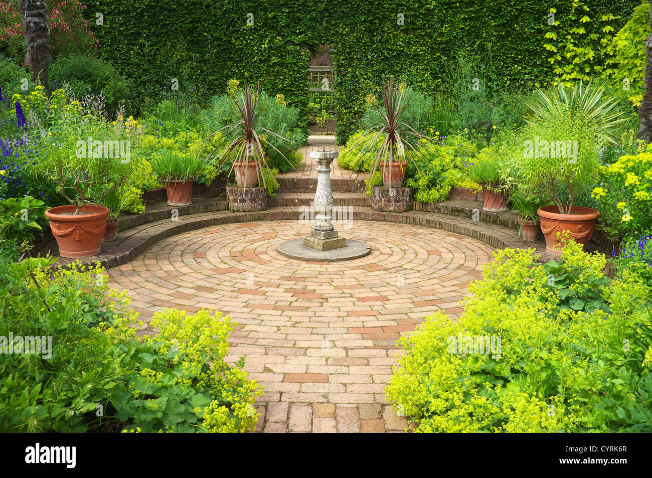 Paved brick garden path leading to Sundial in circular paved area, England UK Stock Photo