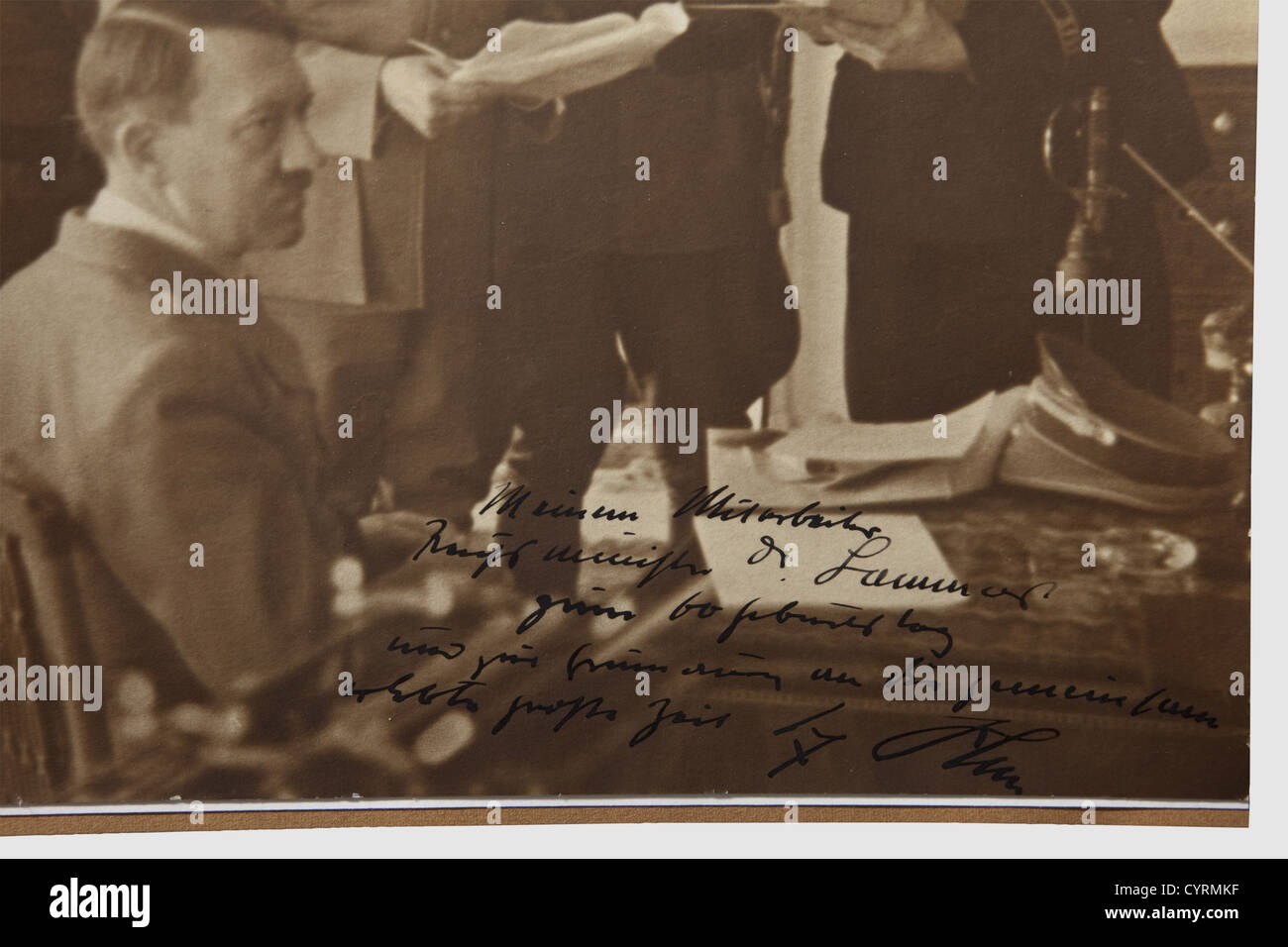 Adolf Hitler,a photograph dedicated to Hans-Heinrich Lammers on occasion of his 60th birthday Large-sized picture(24 x 23.7 cm trimmed?),Hitler sitting at his desk,in front of him Reichsministers Lammers and Frick as well as Reichsleiter Martin Bormann and SS Gruppenführer Wilhelm Stuckart,the lower edge with handwritten ink dedication "To my assistant,Reichsminister Dr.Lammers,for his 60th birthday and in remembrance of eventful times we went through together - Adolf Hitler." Well readable autograph applied to picture with bold ink ,Additional-Rights-Clearences-Not Available Stock Photo