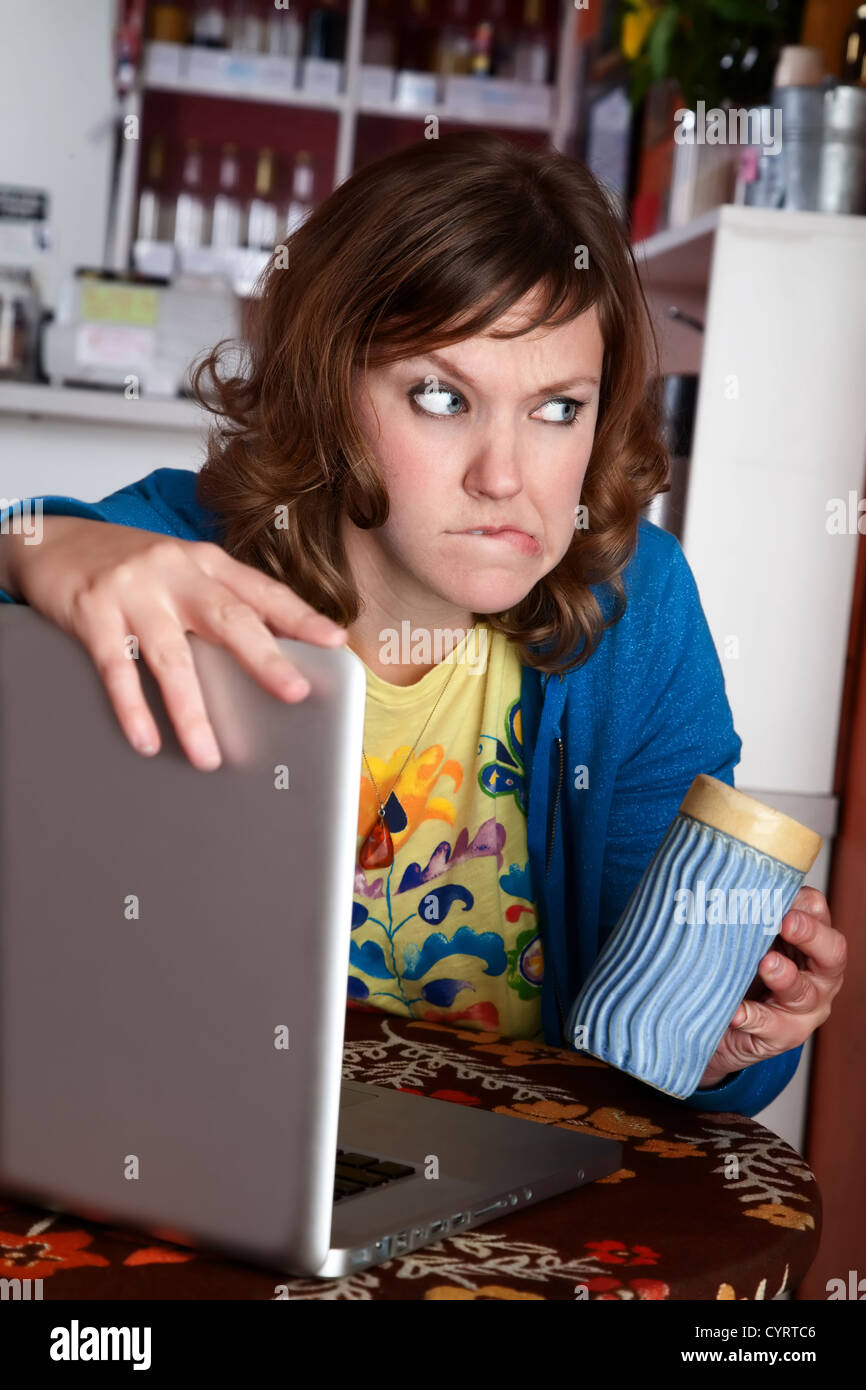 Paranoid lady at cafe with laptop and coffee Stock Photo