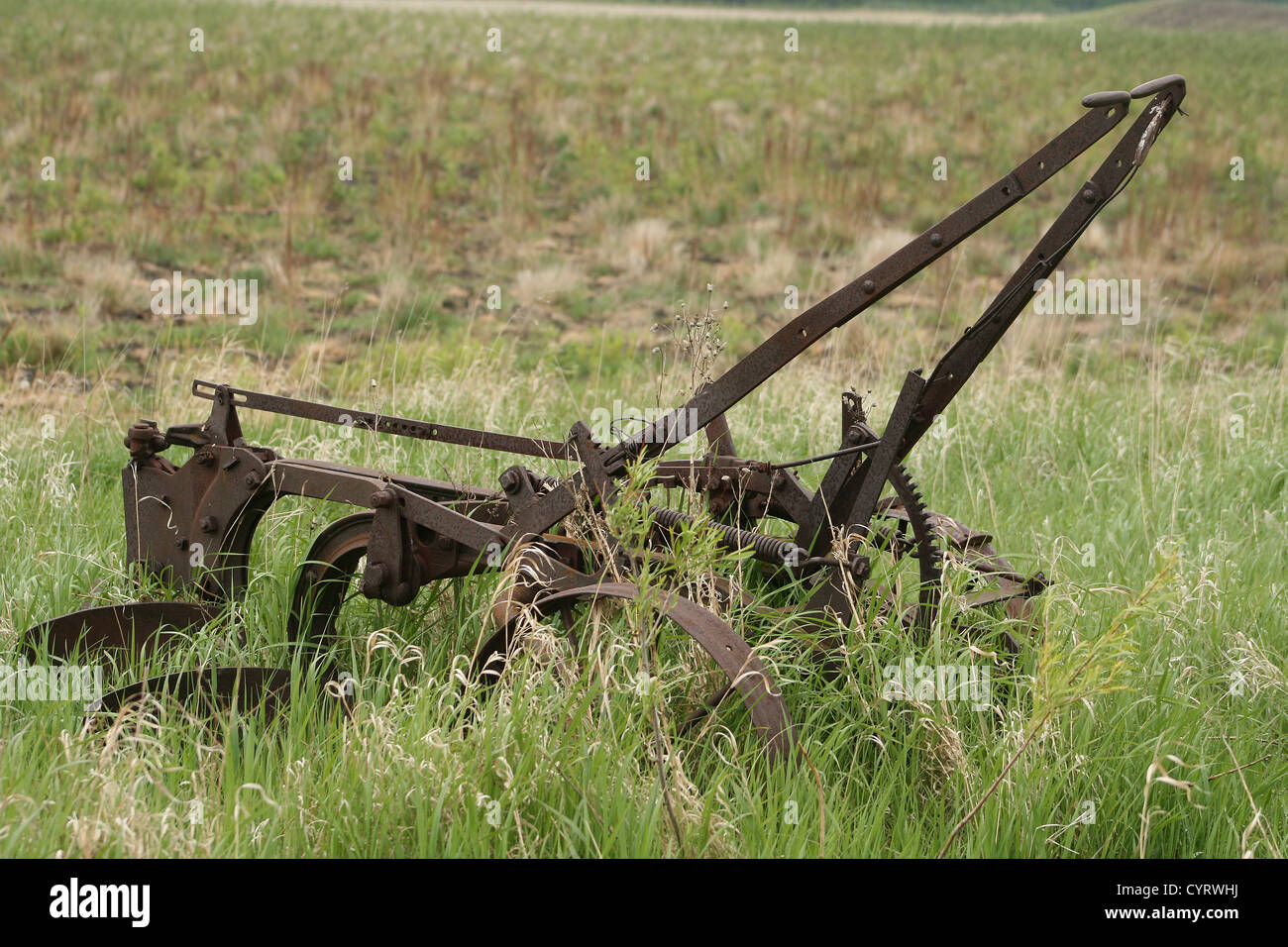 An antique, rust covered two share plow abandoned in a farmers field in spring in Winnipeg, Manitoba, Canada Stock Photo