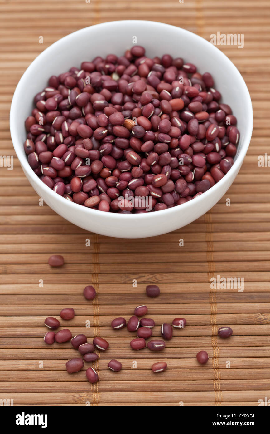 Adzuki beans in a white bowl on a bamboo mat Stock Photo