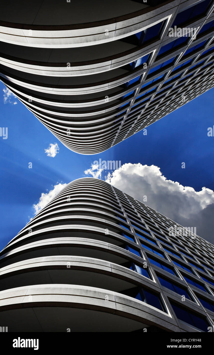 A Symmetrical Digital Composite Of Two Skyscrapers. Looking Up To A Deep Blue Midday Sky With Clouds And Sunburst Stock Photo