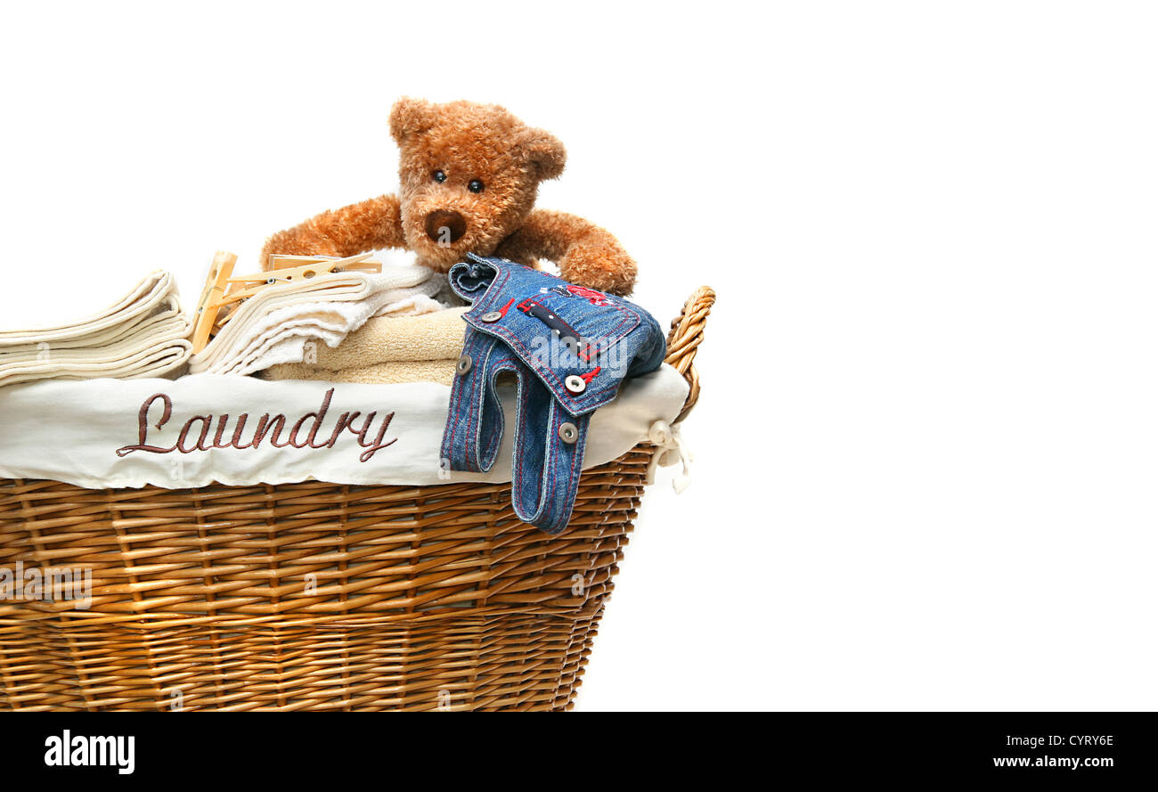 Laundry basket full of towels with teddybear on white background Stock