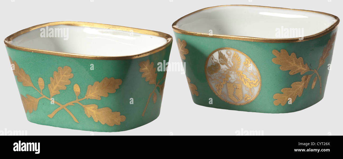 Hermann Göring - two salt bowls,from presentation service by Sèvres factory On occasion of his 50th birthday on 12 January 1943.The white and green glazed porcelain lavishly decorated in gold,the Göring family coat of arms on obverse side and continuous oak leaf decoration.One piece with two chips on gold border.On bottom green underglaze manufacturer's mark and a golden dedication 'Dem Reichsmarschall des Grossdeutschen Reiches Hermann Göring zu seinem 50.Geburtstag 12.Januar 1943'(To Reichsmarschall Hermann Göring on oc,Additional-Rights-Clearences-Not Available Stock Photo